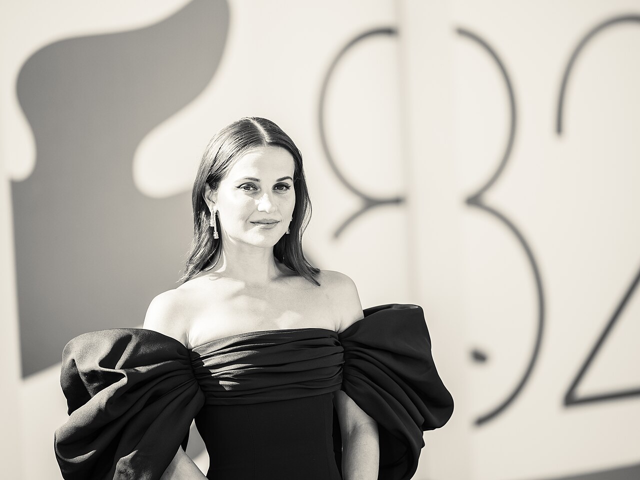 Alicia Vikander posing in a black dress at the 2025 Venice Film Festival