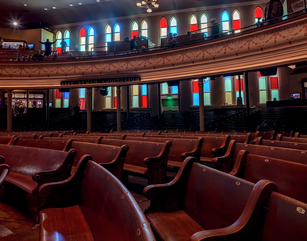 Curved wooden pews and church-like windows inside Ryman Auditorium in Nashville